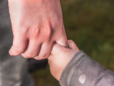 Mano de un adulto sosteniendo la de un niño, símbolo del contacto humano consciente en una meditación guiada sobre la presencia y la conexión.