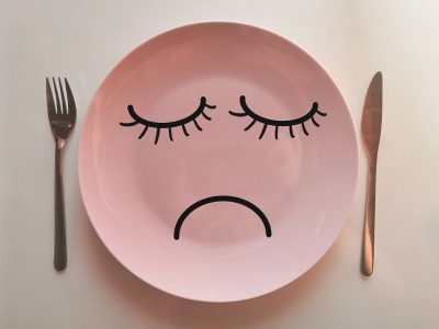 Plato vacío con cara triste que representa la falta de apetito durante la enfermedad, concepto de nutrición durante el tratamiento del cáncer.